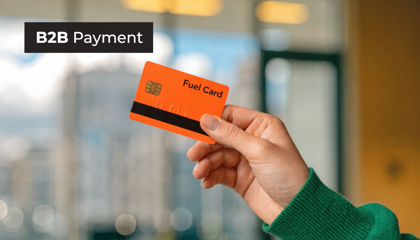 Une main tenant une carte carburant orange pour le paiement interentreprises dans un environnement de bureau professionnel.